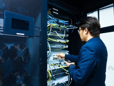 Bir teknisyen, modern dijital altyapıda ideal sistem performansı ve bakımı için gerekli bağlantıları sağlayarak, sunucu odasındaki çeşitli kabloları yönetir..
