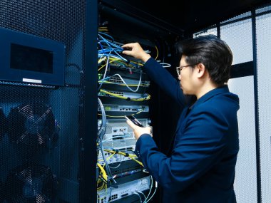 Odaklanmış bir bilişim teknisyeni sunucu odasında ağ ekipmanlarını ayarlar, verimli işlemler için optimum bağlantı ve dijital altyapının performansını sağlar.