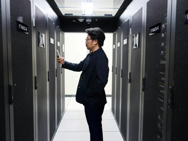 Bir bilişim uzmanı modern bir veri merkezinde sunucu raflarıyla etkileşime girer, bilgi yönetimi alanında teknoloji ve operasyonel mükemmelliğin bir karışımını sergiler.