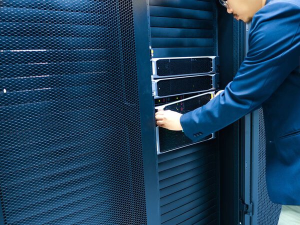 Профессионал настраивает серверное оборудование в современном дата-центре. На этом снимке запечатлена сложность управления технологиями и их обслуживания в ИТ-среде.