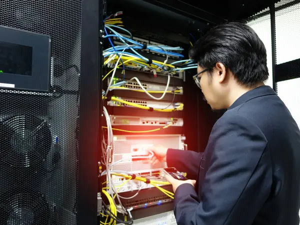 Bir teknisyen, modern veri merkezlerinin karmaşıklığını vurgulamak için bir sunucu rafı içinde bakım yapar. Odaklanmada teknoloji ve altyapı vurgulanıyor.