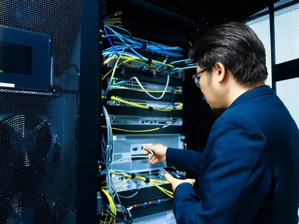 Bir teknisyen veri merkezinde özenle çalışır, kabloları yönetir ve sunucu ekipmanlarının istikrarını sağlar. Organize ortam hassasiyeti ve teknolojiyi yansıtıyor..