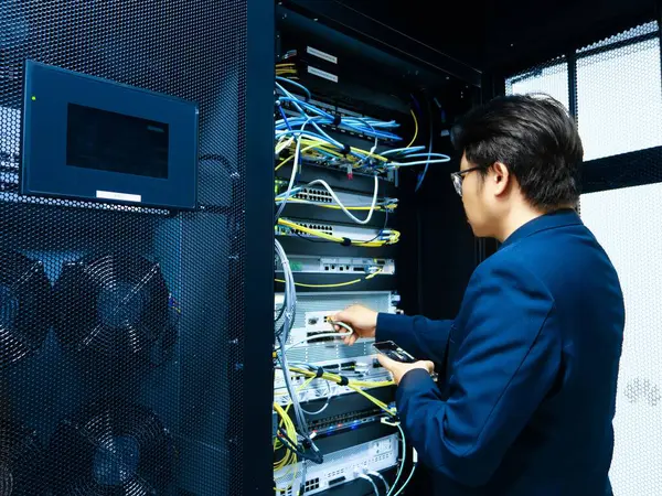 Bir teknisyen, modern dijital altyapıda ideal sistem performansı ve bakımı için gerekli bağlantıları sağlayarak, sunucu odasındaki çeşitli kabloları yönetir..
