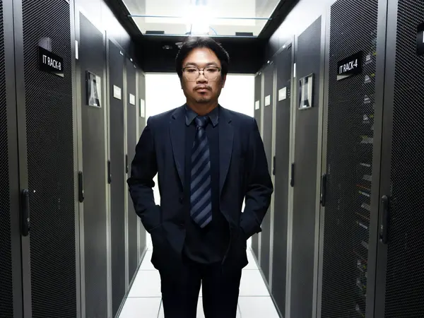 Profesyonel bir bilişim uzmanı, lüks bir sunucu odasında modern teknoloji ve veri yönetimi ve ticari işlemler için gerekli güvenlik sistemlerini sergileyerek güvenle poz veriyor.