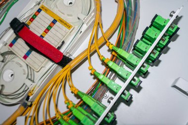 Verimli iletişim ve bilgi aktarımı için kritik bileşenleri gösteren, bir veri ağı kurulumuna bağlı fiber optik kabloların yakın görüntüsü.