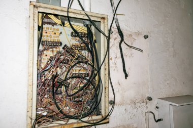 Karışık kablolar ve karmaşık devrelerle dolu dağınık bir elektrik paneli. Bu görüntü elektrik tesisatlarının ve tamiratların kaotik doğasını yakalar..