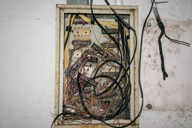 Görüntü, elektrik kontrol panelinin içindeki kabloların düzensizliğini gösteriyor. Sahne, bakım işlerinde sıklıkla görülen karmaşıklık ve düzensizliği resmediyor..