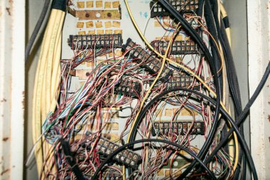 Çeşitli kablolarla dolu karmaşık bir elektrik bağlantı kutusunun yakın çekim görüntüsü, uygun işlev ve güvenlik için hayati önem taşıyan karmaşık ve kaotik düzenlemeyi gözler önüne seriyor.