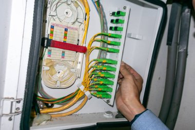 Bir teknisyen, organize fiber optik kablolar ve bağlantıları gösteren, modern teknoloji ve iletişim altyapısını gösteren bir ağ bağlantı panelinde bakım yapıyor..