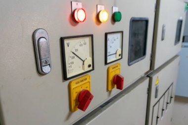 Endüstriyel makinelerde kullanılan göstergeler, voltaj ölçümleri, güvenlik özellikleri ve operasyonel denetimlerde kullanılan metre ve göstergelerin yer aldığı bir kontrol panelinin resmi.