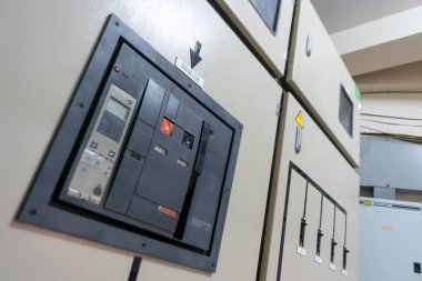 Endüstriyel bir tesis içindeki bir kontrol panelinin yakın görüntüsü, etkin güç yönetimi için elektrik dağıtım elementleri ve güvenlik anahtarları sergileniyor.