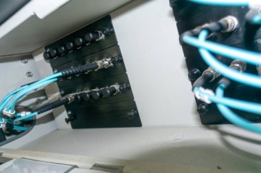 Bu görüntü, çeşitli kablo ve bileşenlerin bağlantısını ve organizasyonunu vurgulayarak, ekipman dolabının içindeki elektrik kablolarını karmaşıklaştırır..