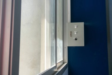 Modern bir iç mekanda pencerenin yanına monte edilmiş bir kontrol paneli. Bu resim, iç mekan ortamında teknoloji ve tasarım sergiliyor..