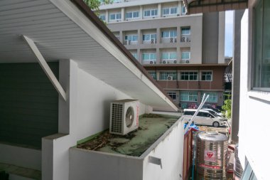 Bu fotoğraf şehirdeki apartmanların arka planına karşı eğimli bir çatıdaki klimayı gösteren kentsel bir çatı görüntüsü..