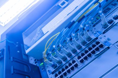 Fiber optik bağlantılar ve kabloların sergilendiği modern bir ağ dolabının yakın çekim görüntüsü. Bu görüntü iletişimdeki teknolojik yeniliği temsil ediyor..