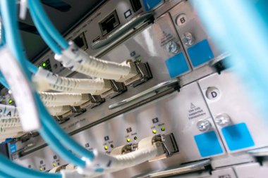 Ağ ekipmanlarının detaylı yakın çekim görüntüsü, kablolar ve bir sunucudaki bağlantılar. Resim dijital altyapıdaki teknoloji ve veri yönetimini vurguluyor.