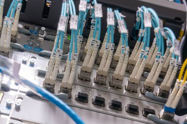 Modern iletişim sistemlerindeki teknoloji ve veri iletimini vurgulayarak, ağ donanımına bağlı yüksek çözünürlüklü yakın çekim fiber optik kablolar sergiliyor.