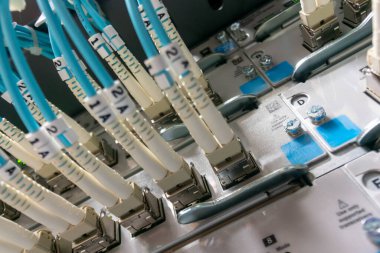 Bir veri merkezine bağlı fiber optik kabloların yakın görüntüsü, modern teknolojiyi ve kusursuz iletişim için gelişmiş ağ altyapısını sergiliyor.