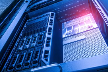 Güvenli bir ortamda yumuşak mavi ışıkla aydınlatılan birden fazla depolama ünitesi ve gelişmiş teknolojiyi gösteren bir sunucu rafının yakın çekim görüntüsü.