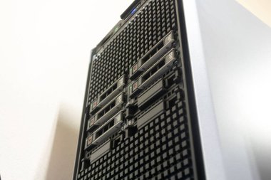 Profesyonel bir bilgisayar ortamında modern teknoloji ve veri depolama verimliliğini vurgulayan çoklu sürücü bölmelerini gösteren bir sunucu kulesinin yüksek açılı görüntüsü.