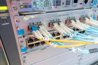 Fiber optik kabloların yer aldığı ağ ekipmanlarının yakın görüntüsü, bağlantı portlarının ve modern iletişim için gerekli dijital altyapının sergilenmesi.