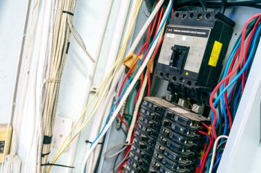 Elektrik panelinin yakın çekim görüntüsü devre kesicileri ve renkli kabloları gösteriyor. Elektrik sistemleri, güvenlik ve bakım hizmetleri ile ilgili konular için ideal.