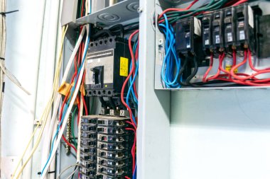 Bu resim, kurulum ve bakım uygulamalarını gösteren çeşitli kablo ve bağlantıların yer aldığı bir elektrik devre kesici panelinin ayrıntılı bir görünümünü gösterir..