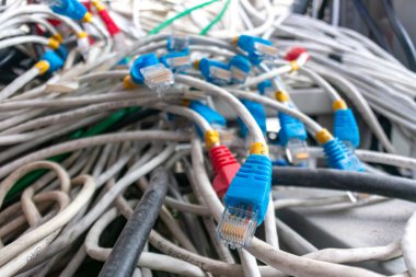 Çeşitli renklerde ethernet kablo ve kablolarından oluşan kaotik bir karmaşanın yakın plan görüntüsü. Bu resim teknoloji düzenlemelerinde bulunan karmaşıklığı ve düzensizliği vurgular.