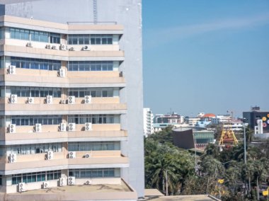 Ön cephesinde sayısız havalandırma ünitesi bulunan çağdaş bir şehir binası. Parlak güneşli bir gün şehir hayatının berrak görüntüsünü artırır..