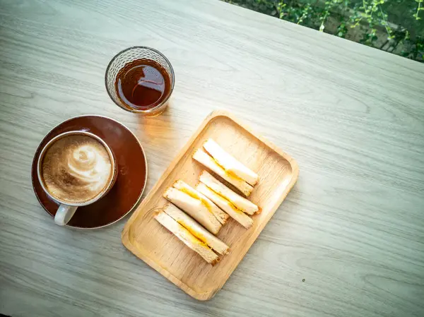 Bir fincan kahvenin ve ahşap bir masada atıştırmanın keyfini çıkarın. Rahatlama ve hoşgörü anları yakalamak için mükemmel..