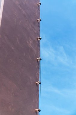 Modern bina cephesinin çarpıcı bir görüntüsü, temiz çizgiler ve geometrik şekiller, parlak mavi gökyüzüne karşı, mimari tasarımı vurguluyor..