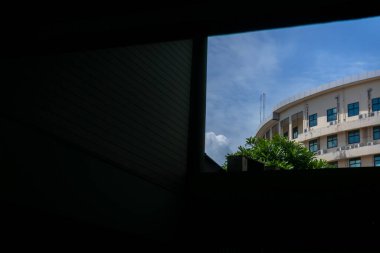 Parlak bir gökyüzüne bakan, karanlık bir pencere çerçevesinden ışık ve perspektifin güzel bir kontrastını yakalayan çarpıcı bir görüntü..