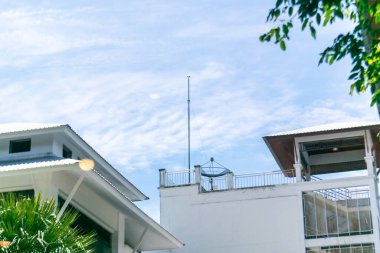 Parlak mavi bir gökyüzü altında modern mimariyi gözler önüne seren çarpıcı bir görüntü. Parlak çizgiler ve yeşillik ferahlatıcı bir şehir manzarası yaratır. Tasarım için mükemmel..