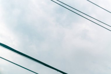 Tepesinde elektrik hatları bulunan bulutlu bir gökyüzünün sakin bir görüntüsü. Görüntü, sakin ve modernlik hissi uyandıran kentsel bir atmosfer yakalıyor..