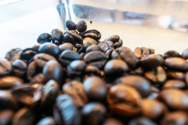 Kahveciler ve yemek fotoğrafçıları için ideal olan zengin dokularını ve aromalarını sergileyen koyu kavrulmuş kahve çekirdeklerinin yakın plan çekimi..