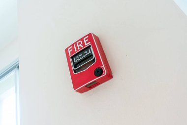 Duvara monte edilmiş parlak kırmızı bir yangın alarmı. Güvenlik ve acil durum hazırlığını vurguluyor. Yangın durumunda kullanıcıları uyarmak için gereklidir.