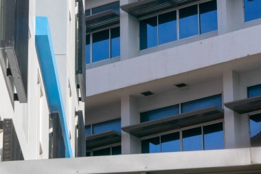 Modern bir bina cephesi, çağdaş mimari tasarımı vurgulayarak, temiz çizgiler ve büyük cam pencerelere çarpıcı bir mavi aksan sergiliyor..