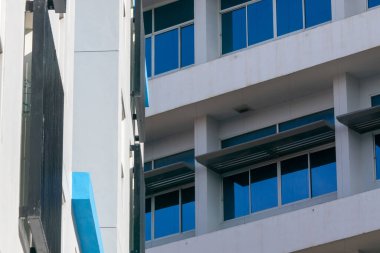 Cam bir cephe ve mavi aksanlı modern mimari tasarıma yakından bakmak, temiz çizgiler ve kentsel bir ortamda minimalist ayrıntılar sergiliyor.