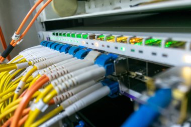 Bir veri merkezinde ağ ekipmanlarının kapatılması, fiber optik kablolar ve LED göstergeleri sergilenmesi, modern iletişim teknolojisi ve altyapısını gösteren.