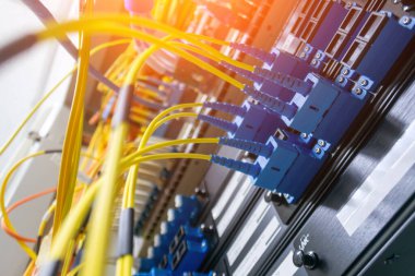 Veri merkezi rafındaki fiber optik kabloların yakın görüntüsü veri iletimi ve iletişiminde kullanılan karmaşık bağlantıları ve modern teknolojiyi gözler önüne seriyor..