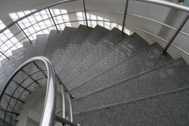 Pürüzsüz çizgileri ve parlak gri yüzeyi olan modern bir spiral merdiven. Zarif tasarım mimari alanda davetkar bir atmosfer yaratıyor..
