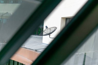 Dışarıdaki bir binaya yerleştirilmiş bir uydu anteni kentsel teknoloji ve iletişim sistemlerini gösteriyor. Bu açı, modern kurulumların benzersiz bir görünümünü sağlar..