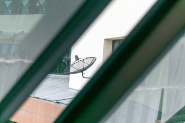 Modern bir binaya yerleştirilmiş uydu anteninin yakın görüntüsü. Fotoğraf, teknolojinin modern mimariyle bütünleşmesini yakalıyor..