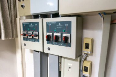 Elektrik şalterleri, şalterler ve göstergelerin yer aldığı, elektrik yönetimi ve güvenlik için gerekli bileşenleri gösteren bir kontrol panelinin ayrıntılı bir görüntüsü.