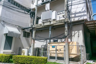 Şehir altyapısını ve enerji yönetimini yakalayan, bir şehir binasına karşı kurulan elektrik hatlarını ve ekipmanlarını gösteren kentsel hizmet kurulumunun ayrıntılı bir görüntüsü.