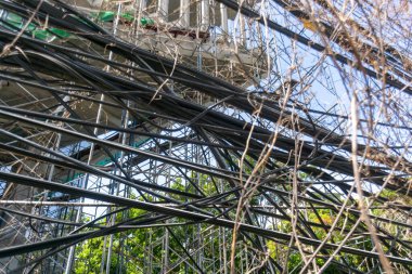 Karışık kablolar ve iskelelerin sergilendiği, kentsel gelişimin ve doğanın kesişiminin vurgulandığı bir inşaat alanının ayrıntılı bir görüntüsü.