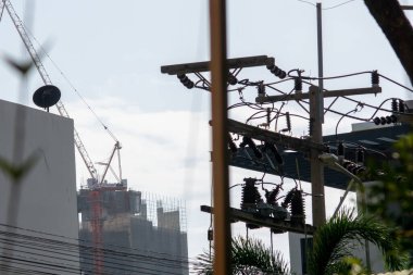 A construction site showcasing a crane and power lines under a clear blue sky. The image captures urban development and industrial progress in motion.