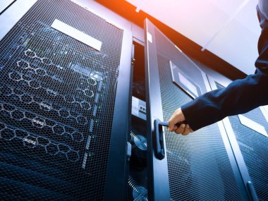 Modern bir veri merkezinde sunucu dolabı açan bir elin yakın plan görüntüsü, ileri teknoloji ve bilgi yönetimi için kritik bileşenler sergiliyor.