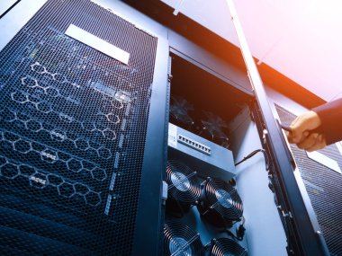 Veri yönetimi ve sunucu işlemleri için kullanılan karmaşık teknolojiyi vurgulayan soğutucu fan ve ağ ekipmanlarının yer aldığı bir sunucu rafının ayrıntılı görünümü.