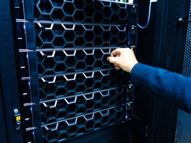 Profesyonel bir el, gelişmiş donanım organizasyonu ve bakımı sergileyen yüksek teknolojili bir veri merkezindeki bir sunucuyu ayarlar. Teknolojiyle ilgili konular için ideal.